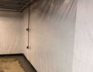 Skilled technician strategically places a waterproof vapor barrier on basement walls, a vital step in preventing dampness. Rely on Premier Basement Systems for expert waterproofing solutions.