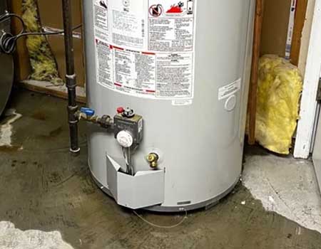 Photograph showing a water heater with visible failure and leakage, highlighting the importance of preventive measures and maintenance to avoid water damage.